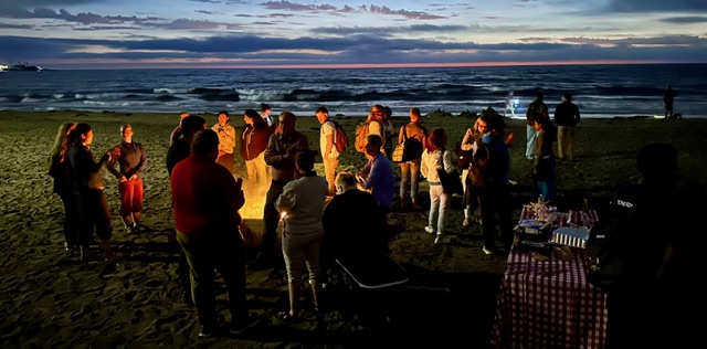 Evening beach gathering with course participants socializing at sunset