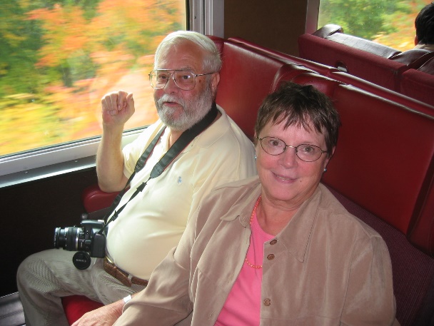 Two course participants on a scenic train through autumn foliage